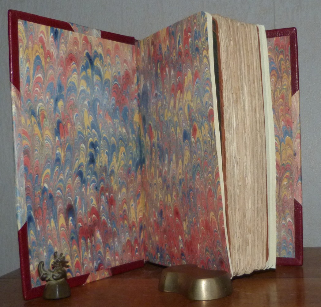 Demi-cuir à coins bordeaux, mosaïques sur le dos du livre reprenant une partie de la couverture du livre