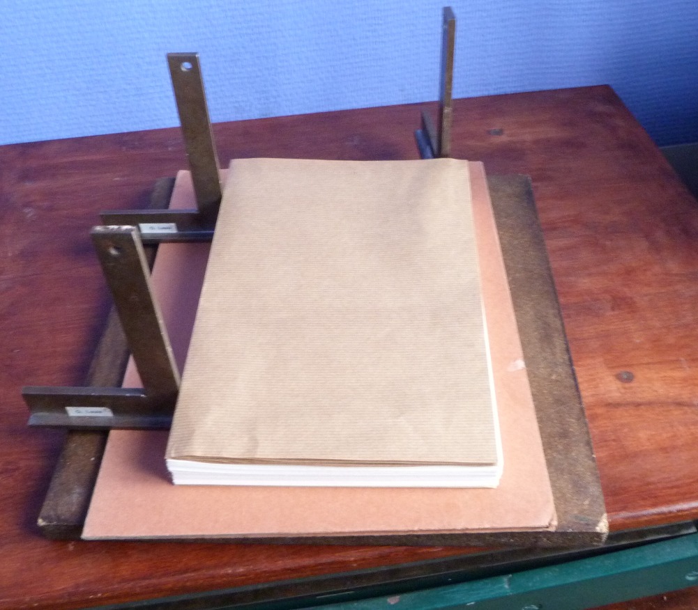Cahier de papier kraft déposé sur une reliure en cours de fabrication