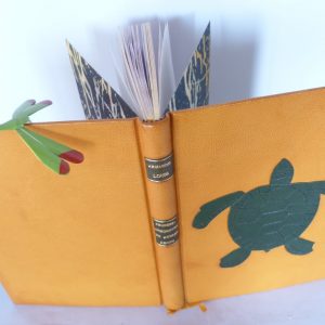 Reliure plein cuir jaune avec une mosaïque verte représentant une tortue. Vue du dessus.